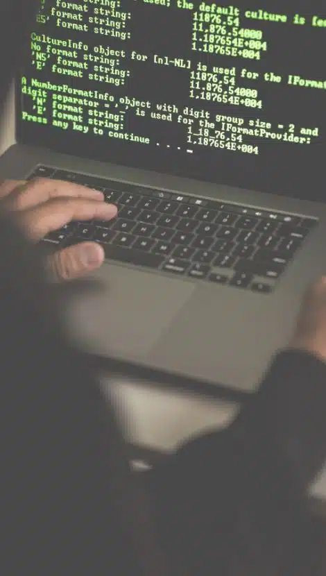 looking over shoulder of a shadowy hacker going through computer code