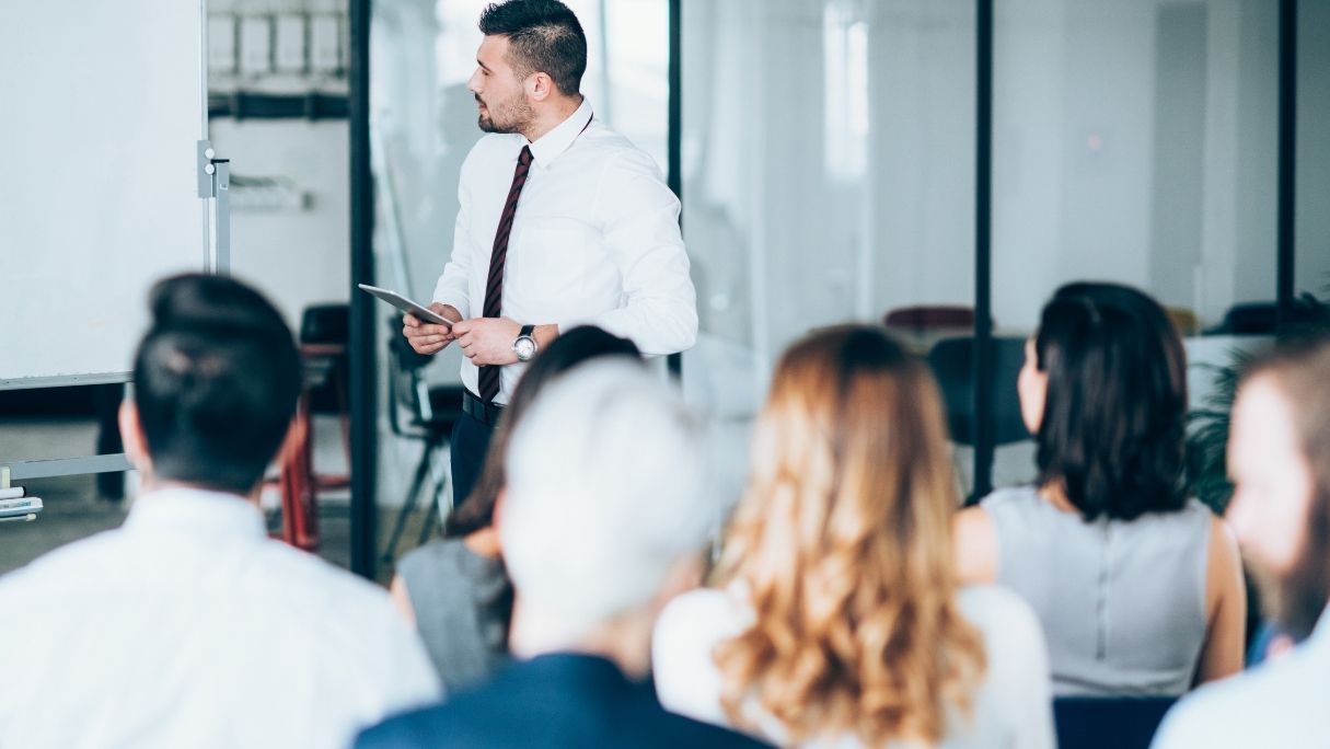 employee cybersecurity training session with attendees looking art presenter with whiteboard